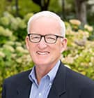 Man with Glasses and Blurred Tree Background