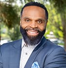 orlando williams headshot. man in blue suit with nature background