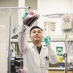 a19_2994 Man in a Lab Coat and Gloves Hanging Bags of Blood in a Laboratory