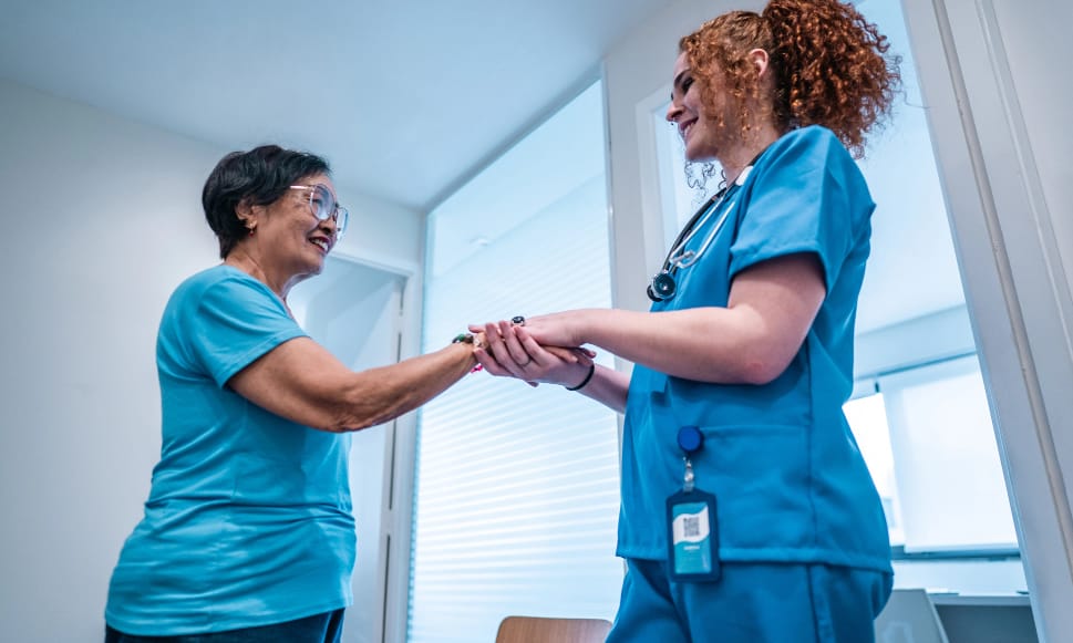 Two women, one a nurse, holding the other woman's hand